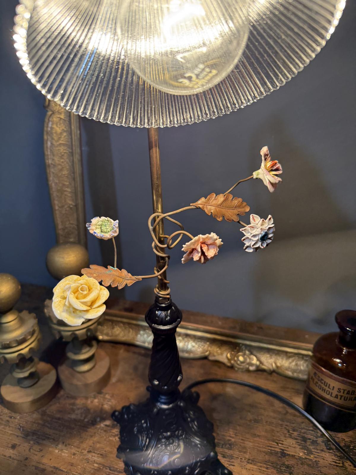 Lampă veche recondiționată, cu flori din ceramică și abajur de sticlă tip Holophane, picio­r din zamac negru mat – sertar magic București.