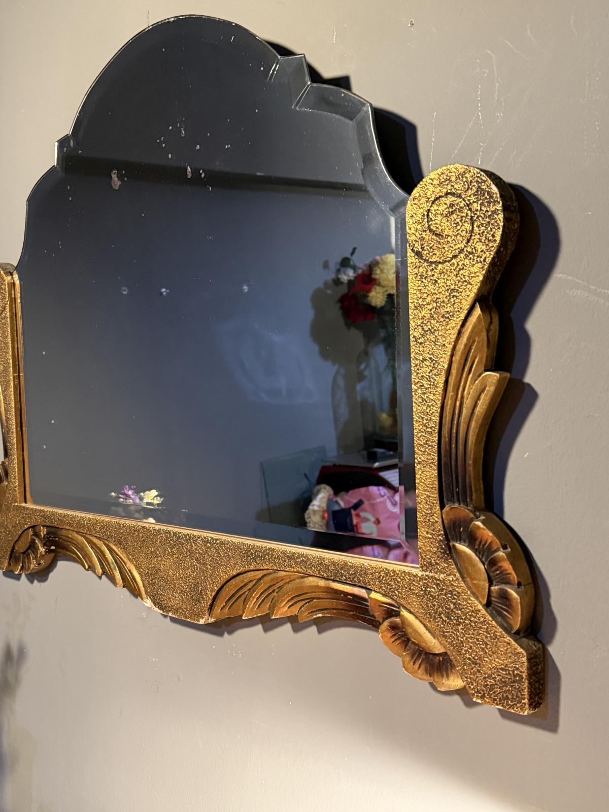 Oglindă veche biseautată cu formă conturată și decor auriu cu frunze și volute. Piesă în stare foarte bună, 76 × 58 cm.