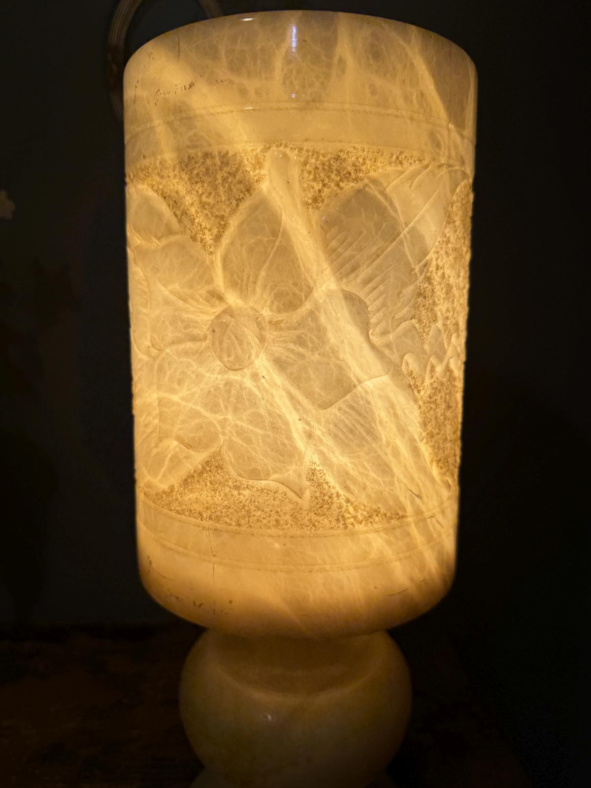 Lampă de masă din alabastru masiv, cu abajur cilindric sculptat cu motive florale. Înălțime 39,5 cm, stare foarte bună.
