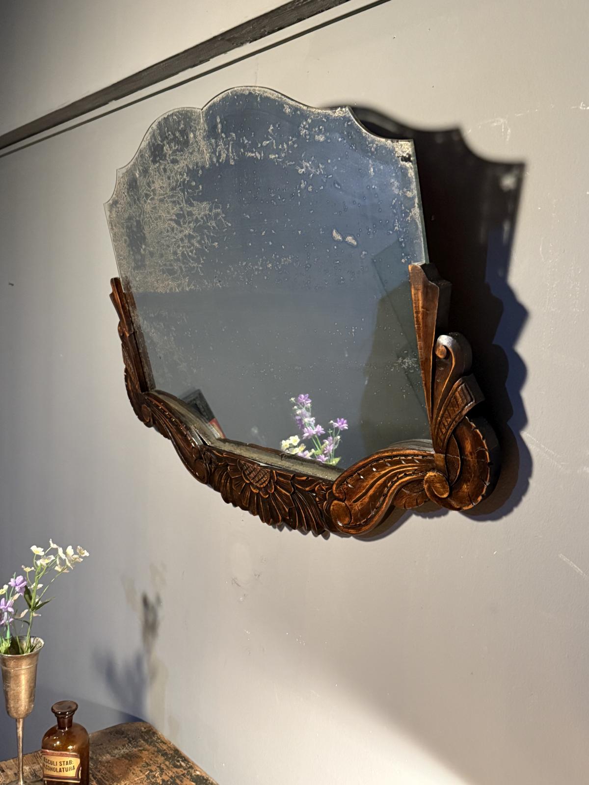 Oglindă veche de 78 × 54 cm, cu ramă sculptată din lemn și patină accentuată pe suprafața oglinzii. Rama a fost reparată.