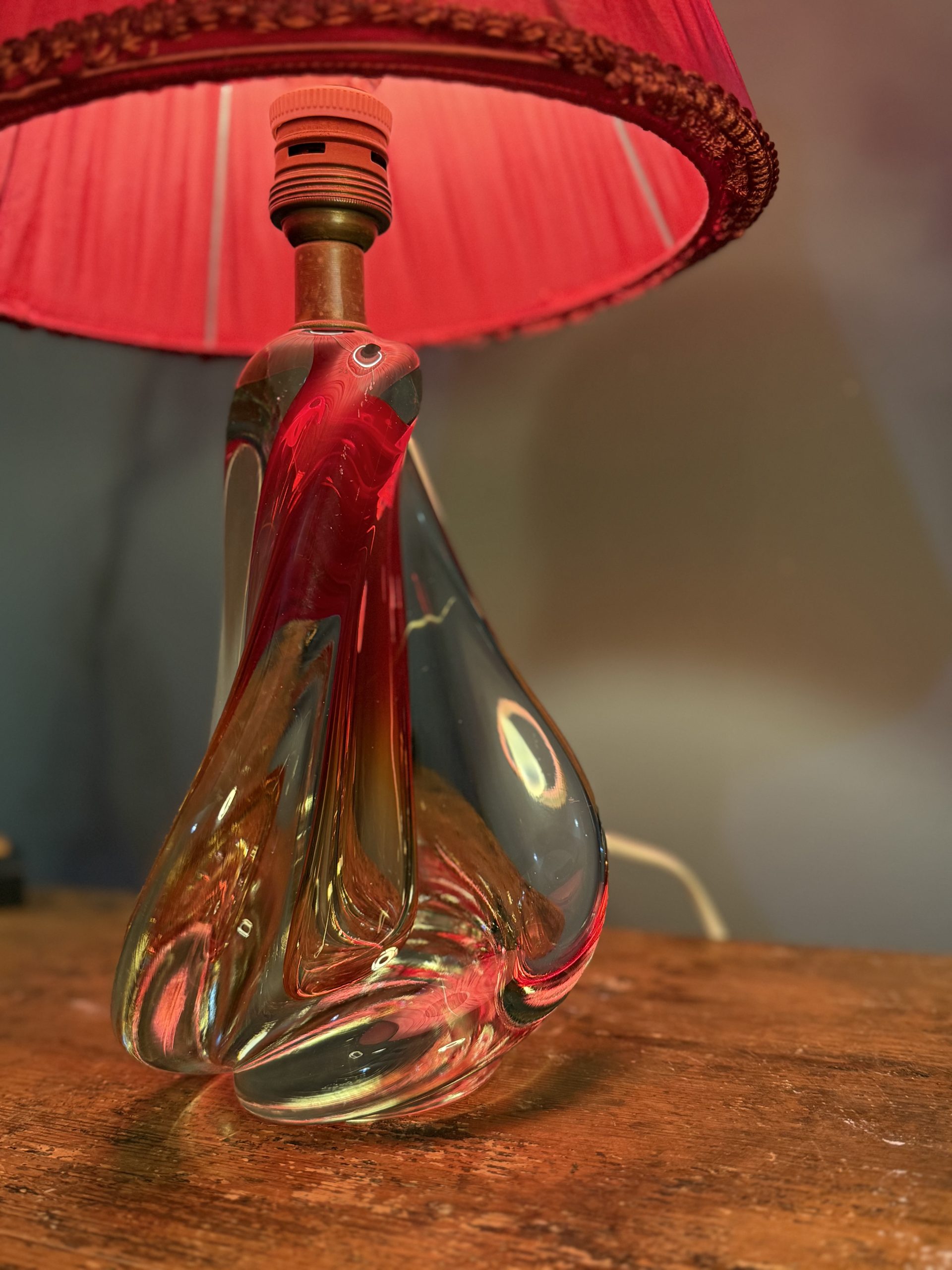 Lampă de masă din cristal masiv, cu formă sculpturală și abajur vechi din material textil roșu. Înălțime totală 47 cm.