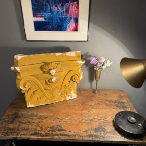 Capitel decorativ din ipsos, cu volute și frunze de acant în relief. Patină ocru, urme de uzură și ciobituri. Dimensiuni: 55 × 40 × 19 cm.