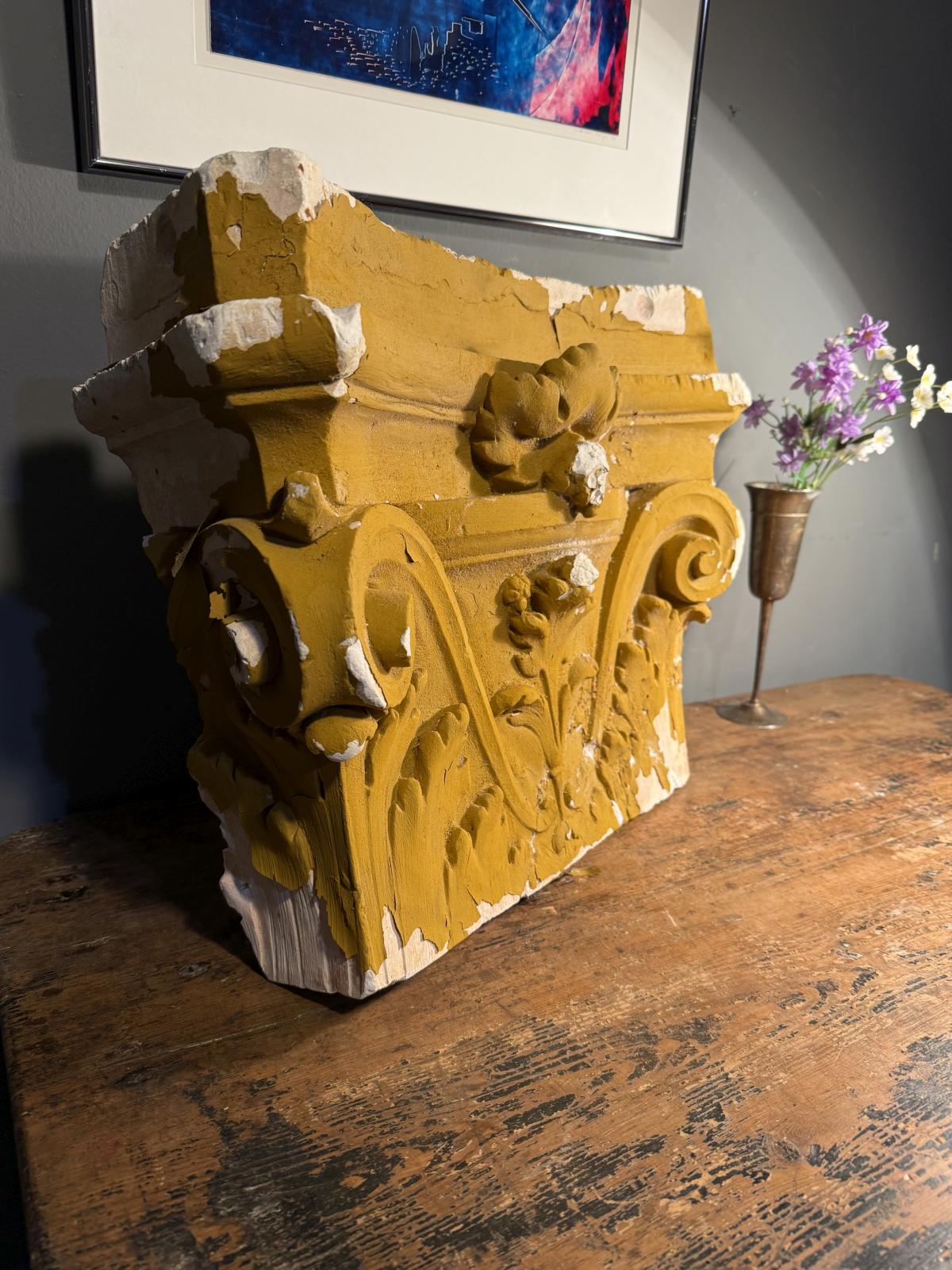 Capitel decorativ din ipsos, cu volute și frunze de acant în relief. Patină ocru, urme de uzură și ciobituri. Dimensiuni: 55 × 40 × 19 cm.