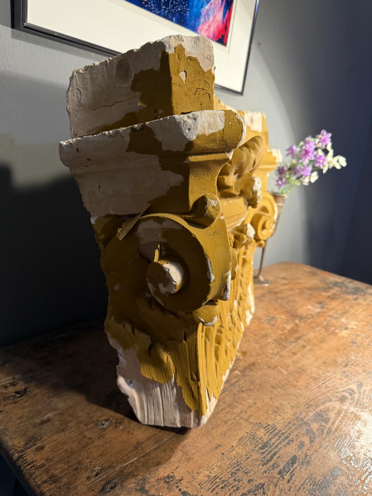Capitel decorativ din ipsos, cu volute și frunze de acant în relief. Patină ocru, urme de uzură și ciobituri. Dimensiuni: 55 × 40 × 19 cm.