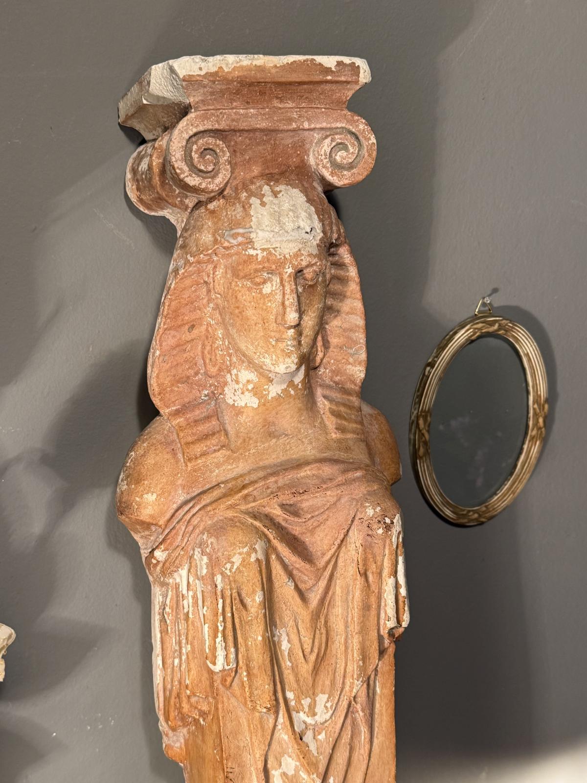 Cariatidă decorativă din ipsos patinat, cu bust feminin și capitel cu volute. Înălțime 71 cm, cu urme de uzură. La Sertar Magic.