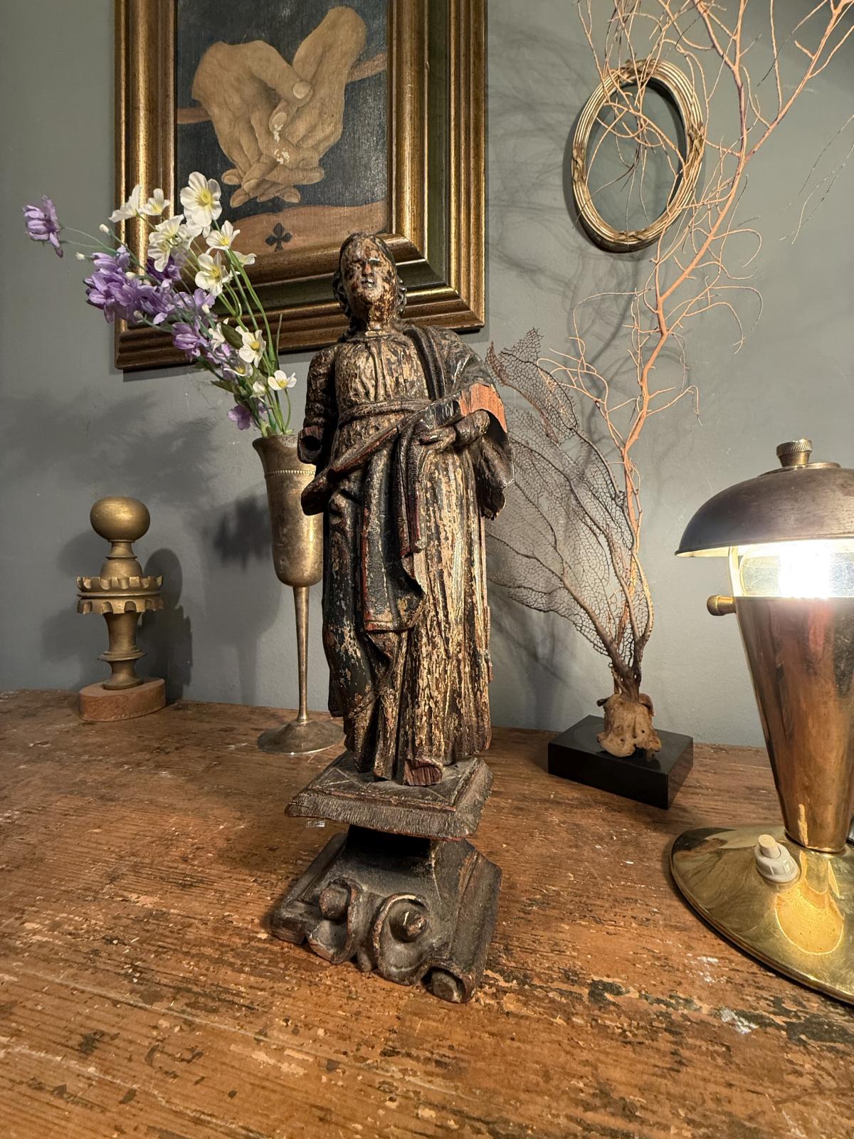 Statuetă religioasă din lemn sculptat, atribuită secolului XVIII, cu urme de policromie și soclu cu volute. Înălțime 28 cm, cu lipsuri.